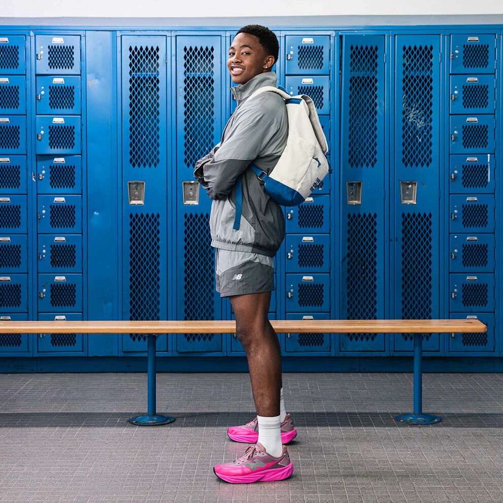 Quincy Wilson wearing the FuelCell Rebel shoes running and waving at a hallway. 